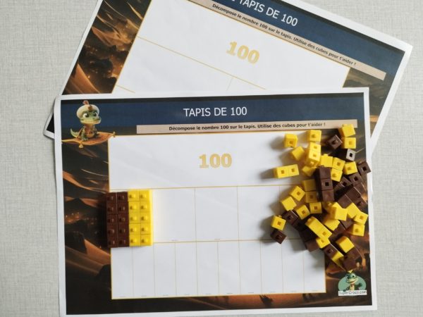 Tapis de nombres avec la décomposition progressive du nombre 100 en centaines, dizaines et unités, accompagné de cubes pour aider les élèves de CE1 à visualiser les différentes parties du nombre.